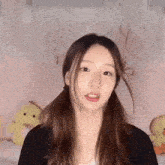 a young woman with pigtails is standing in front of a pink curtain and a stuffed duck .