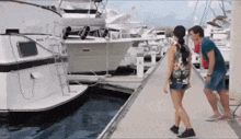 a man and a woman are standing next to a boat that says sail on it
