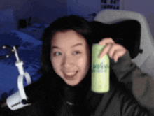 a woman is holding a can of kiwi soda