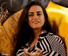 a woman in a black and white striped shirt is smiling and giving a thumbs up