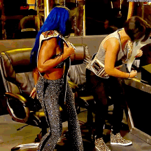 a woman with blue hair is standing next to a man who is writing on a piece of paper ..