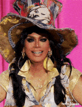 a woman wearing a cowboy hat and hoop earrings smiles for the camera