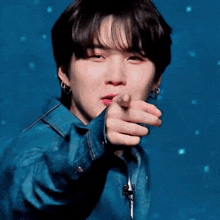 a close up of a person pointing at the camera while wearing a blue jacket .