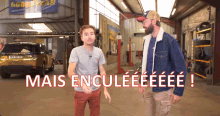 two men are standing in a garage with the words mais enculeeeee written in red