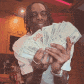 a man in a white shirt is holding a bunch of money in his hands