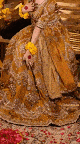 a woman in a yellow dress is standing on a rug covered in petals .