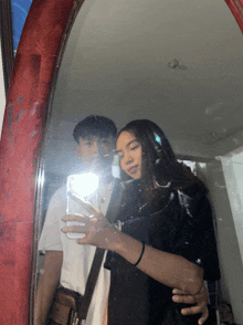 a man and a woman are taking a picture in a mirror