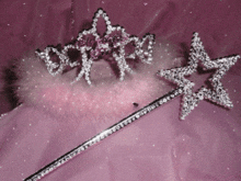 a tiara and a wand are on a pink surface