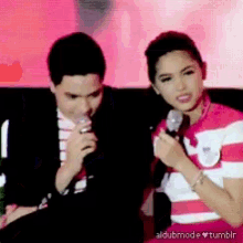 a man and a woman are sitting next to each other and a woman is holding a microphone