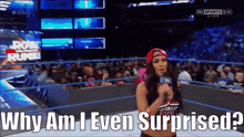 a woman stands in a wrestling ring holding a microphone and says why am i even surprised ?