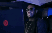 a man wearing sunglasses is sitting in the back of a car .
