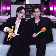a couple of men are sitting on a couch holding toys .