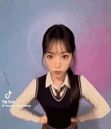 a girl in a school uniform with her hands on her hips .