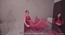 a woman in a red dress is dancing in front of a mirror .