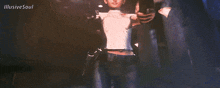 a woman in a white shirt is standing in a dark room with illusive soul written on the bottom of the image
