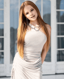 a woman in a white dress stands in front of a white building