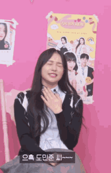 a girl sitting in front of a pink wall with a poster on it that says ' snl ' on it