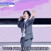 a man in a suit and tie is dancing with the words vote for lee yoonchan above him