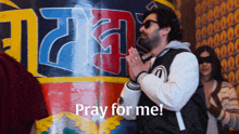 a man prays in front of a sign that says " pray for me "