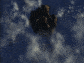 a large rock in the sky with clouds surrounding it