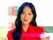 a woman in a red suit is holding a cup of coffee .