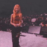 a woman with blonde hair is standing on a stage holding a microphone .