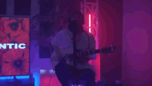 a man is playing a guitar in front of a screen that says ntic