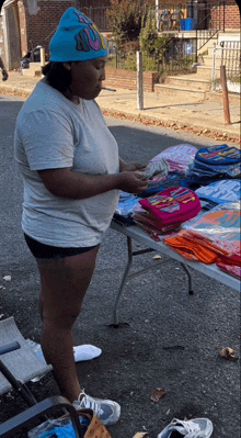 a woman wearing a blue beanie is standing in front of a table holding money