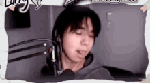a man wearing headphones is sitting in front of a microphone with his eyes closed .