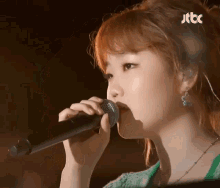 a woman singing into a microphone with jtbc written on the bottom