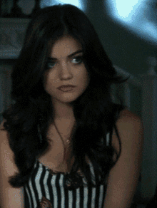 a woman wearing a black and white striped tank top looks at the camera