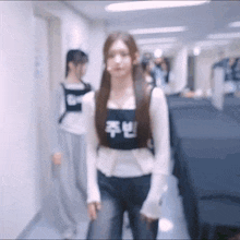 a woman is walking down a hallway wearing a black vest with chinese characters on it .