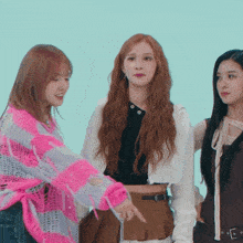 three women are standing next to each other and one of them is pointing at something