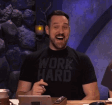 a man wearing a work hard t-shirt is laughing