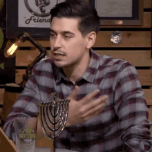 a man in a plaid shirt is sitting at a table holding a menorah
