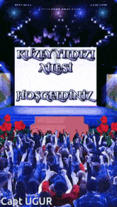 a crowd of people standing in front of a large screen that says kuzey yildizi ailesi hoşgeldiniz
