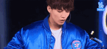 a young man is wearing a blue jacket and a microphone .