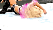 a woman with pink hair is laying on her stomach on the floor .