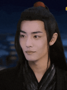 a close up of a man 's face with long black hair