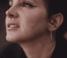 a close up of a woman 's face with earrings on her ear