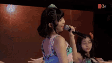 a girl singing into a microphone with the number one on the bottom right