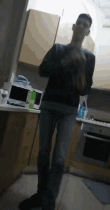 a man standing in a kitchen with a microwave