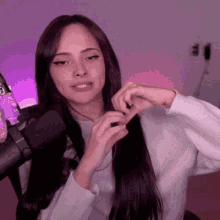 a woman is sitting in front of a microphone and making a heart with her hands .