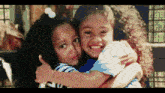 two little girls are hugging each other and one of them is wearing a shirt that says ' i love you ' on it