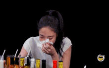 a woman is sitting at a table with bottles of hot sauce and a glass of milk .