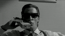 a man wearing sunglasses is talking on a phone that has the letter l on it