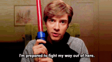 a man is holding a red light saber and says " i 'm prepared to fight my way out of here "
