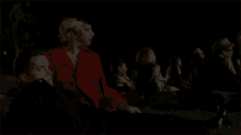 a woman in a red coat sits next to a man in a black shirt