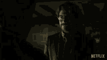 a man in a suit and tie is talking to another man with a netflix logo in the corner