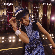 a woman wearing a cowboy hat and a blue dress is dancing on stage